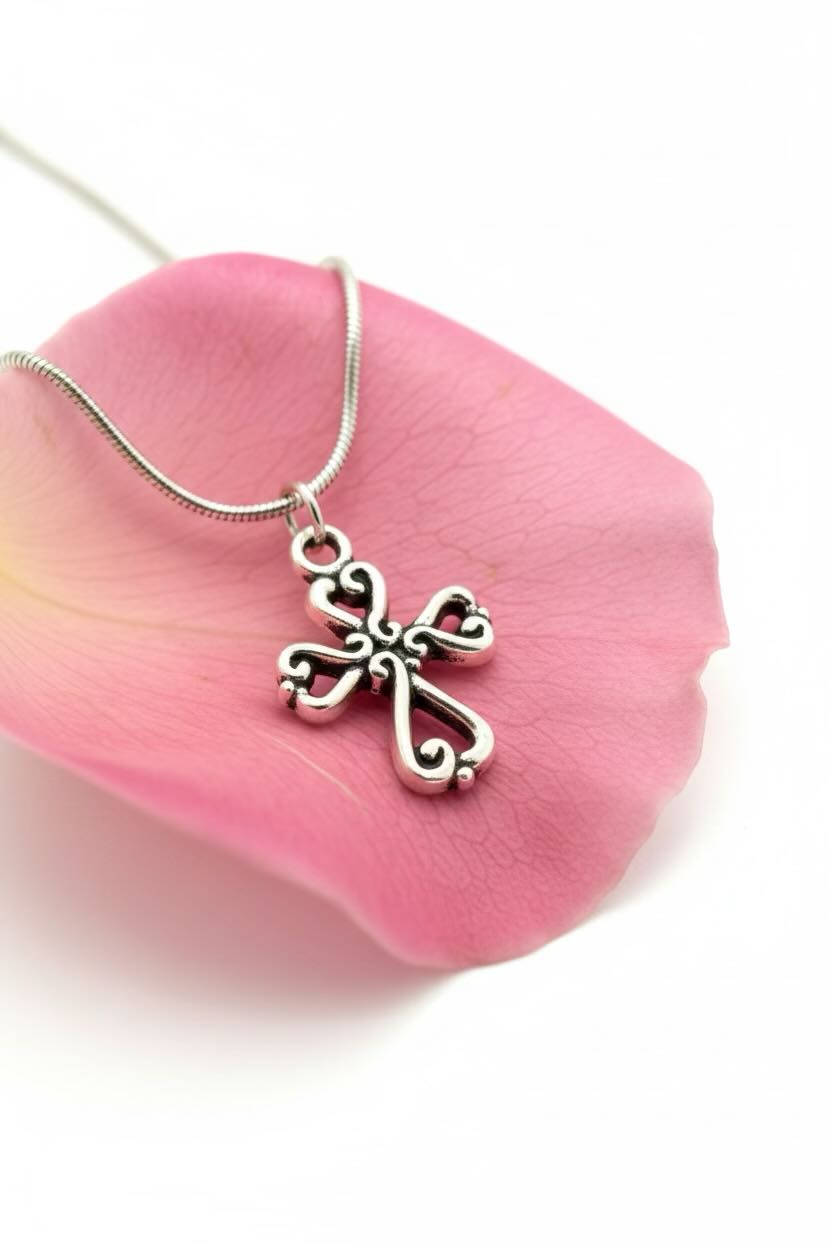 Silver necklace with a cross pendant on a pink petal