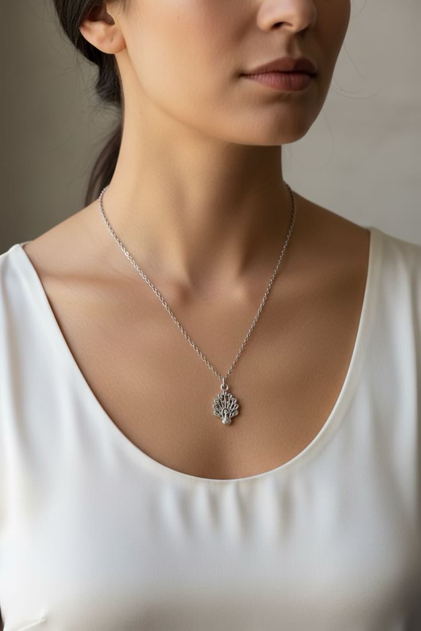 Close-up of a woman wearing a silver necklace with a peacock pendant.