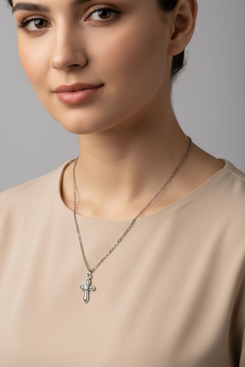 Woman wearing a necklace with a cross pendant against a neutral background