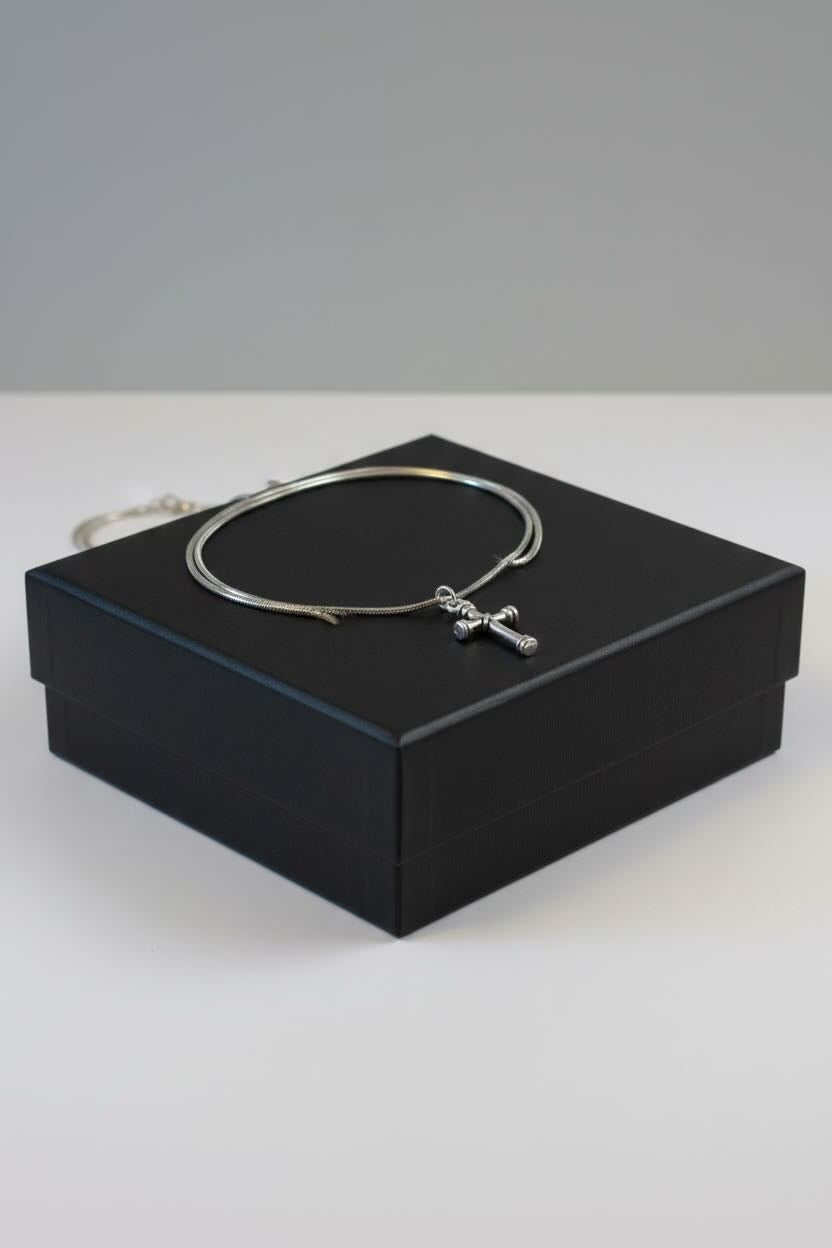 Silver necklace with a cross pendant on a black box