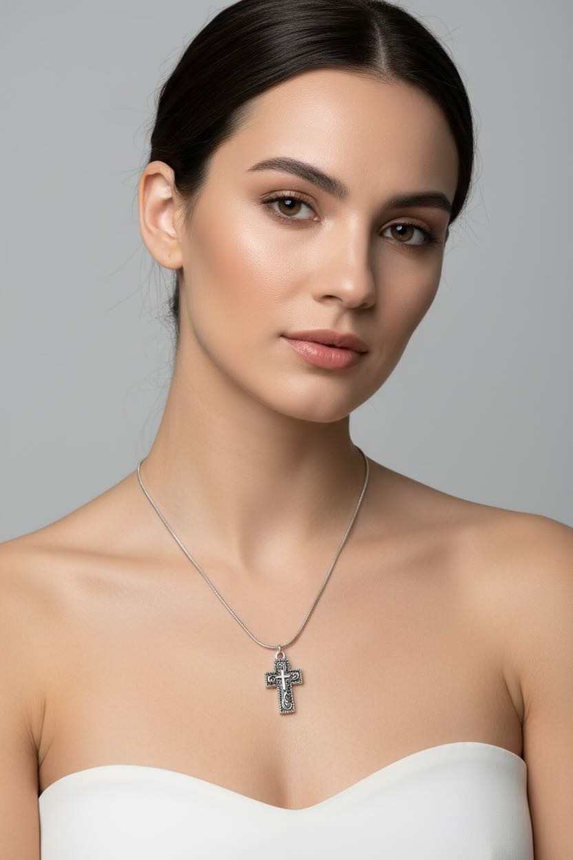 Woman wearing a silver necklace with a cross pendant against a gray background