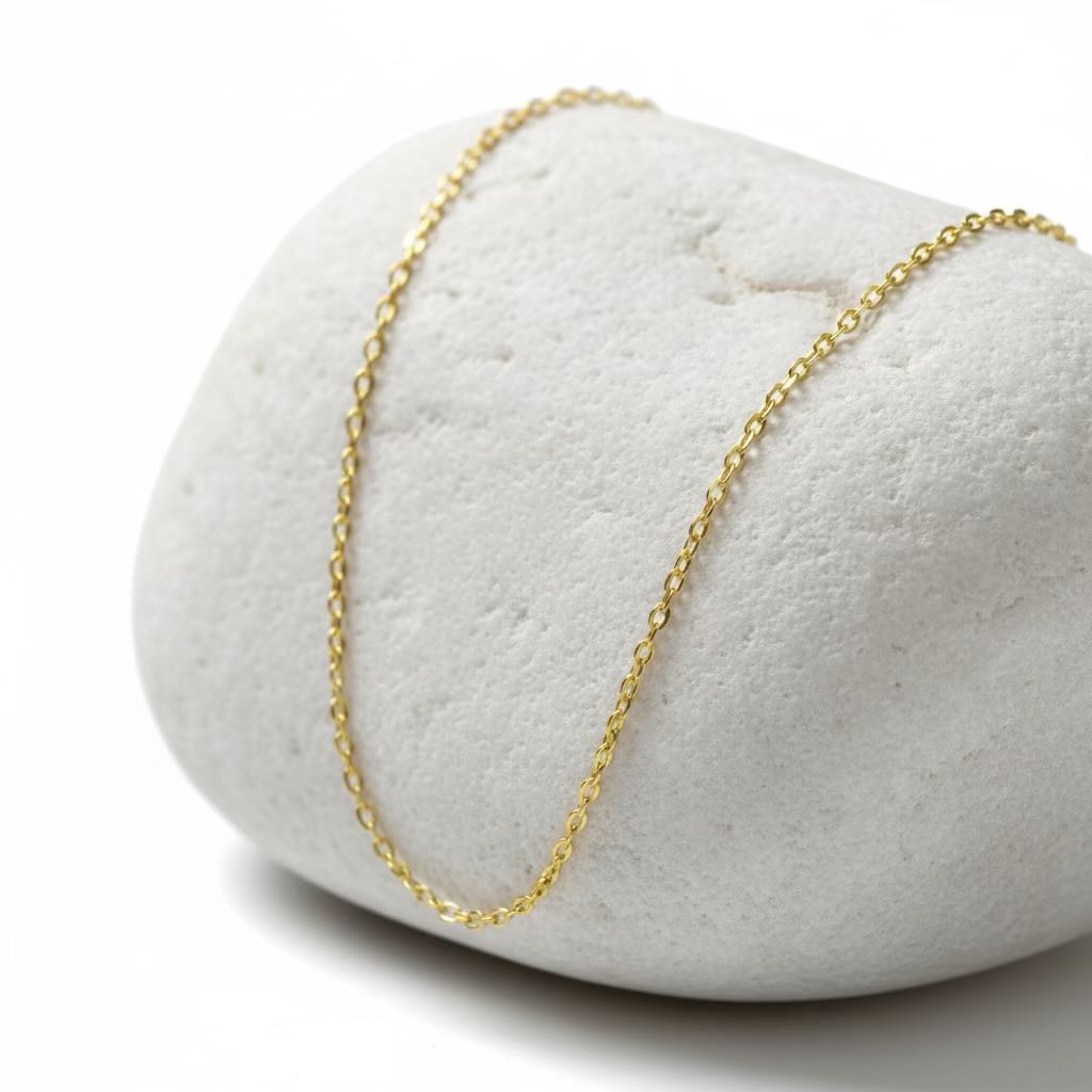 Gold chain necklace on a white stone surface