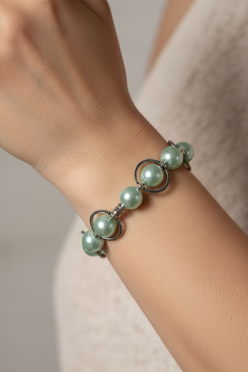 Green pearl bracelet on a wrist with a neutral background