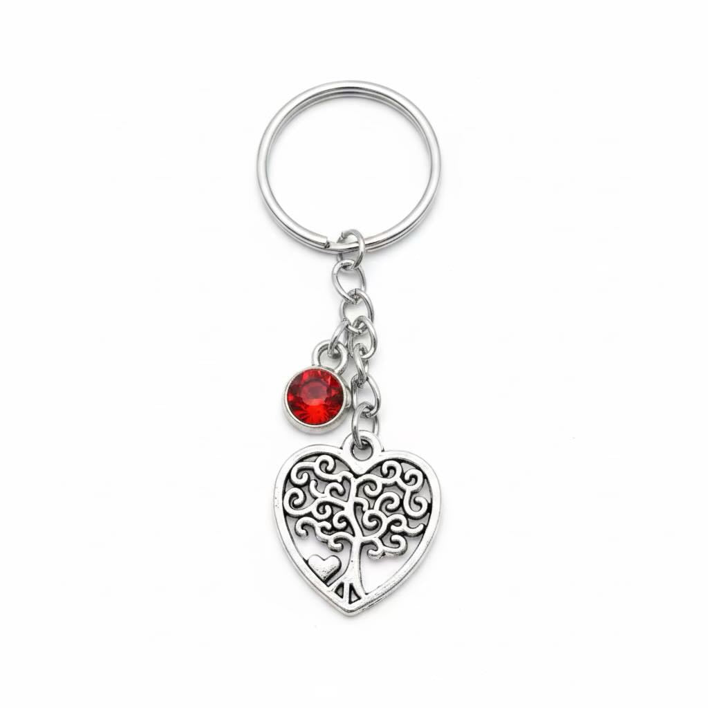 A silver metal keyring/keyrings featuring a heart-shaped filigree tree of life charm and a small red faceted crystal bead, shown on a plain white background.