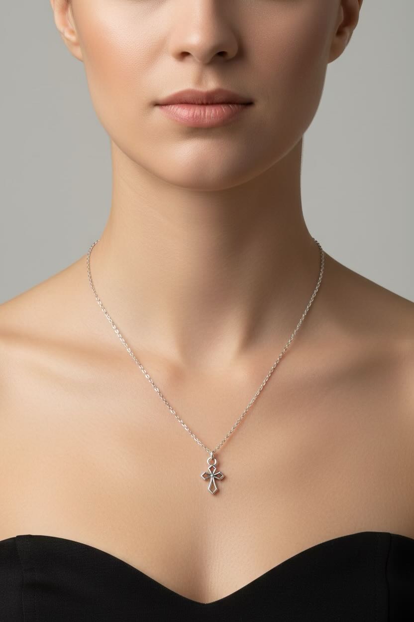 Silver necklace with a cross pendant worn by a person in a black top