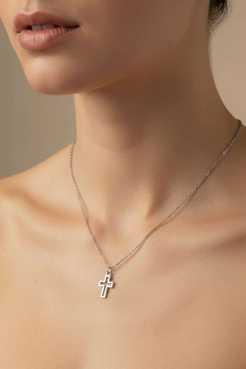 Close-up of a person wearing a silver cross necklace against a neutral background