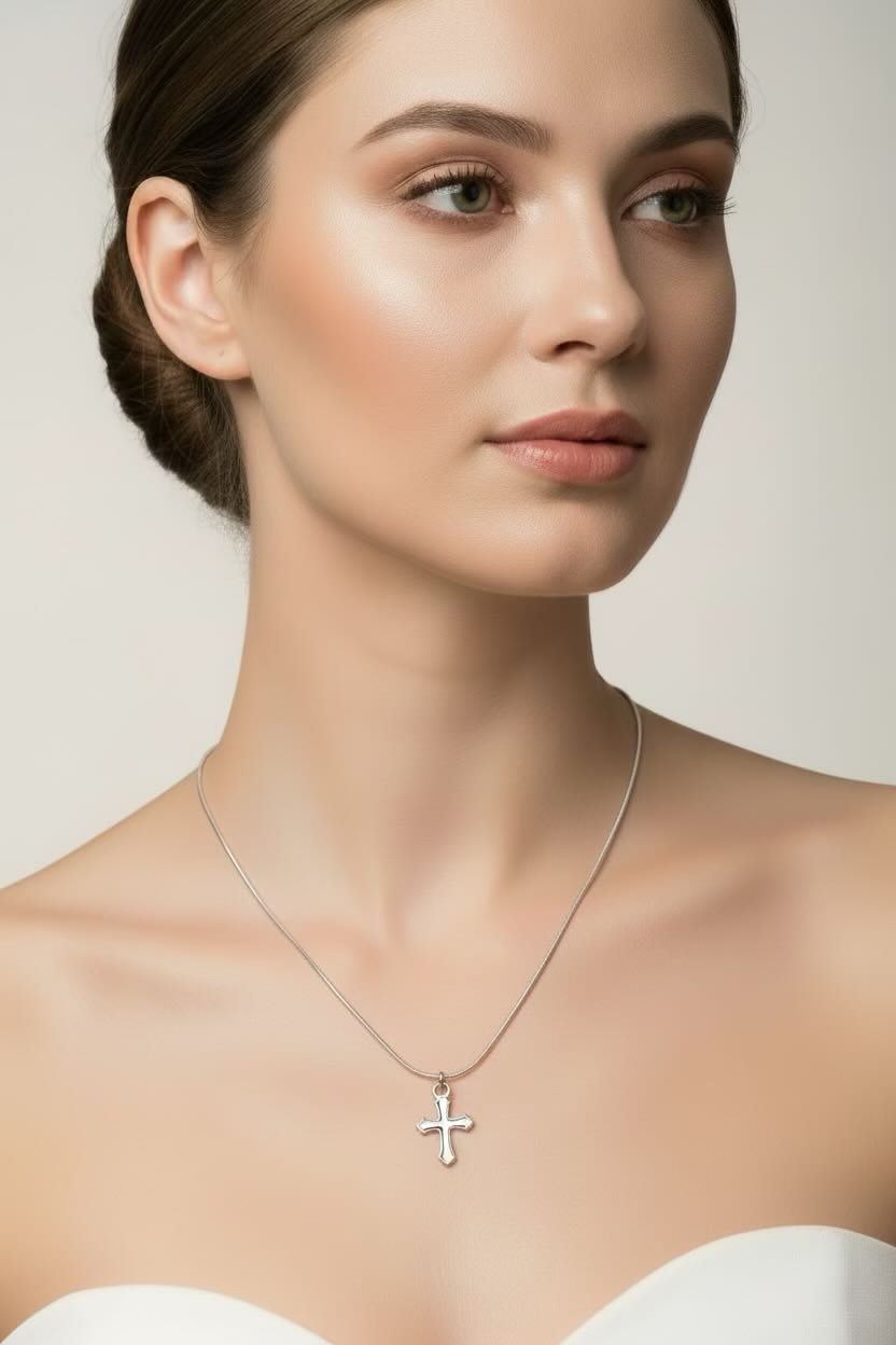 Silver necklace with a cross pendant worn by person in a white top