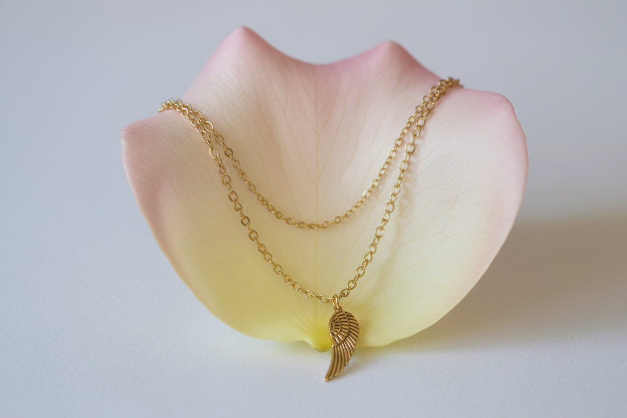 Gold chain necklace with a wing pendant on a large rose petal