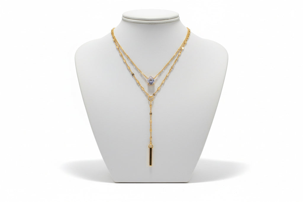Gold necklace with a pendant on a mannequin bust against a neutral background