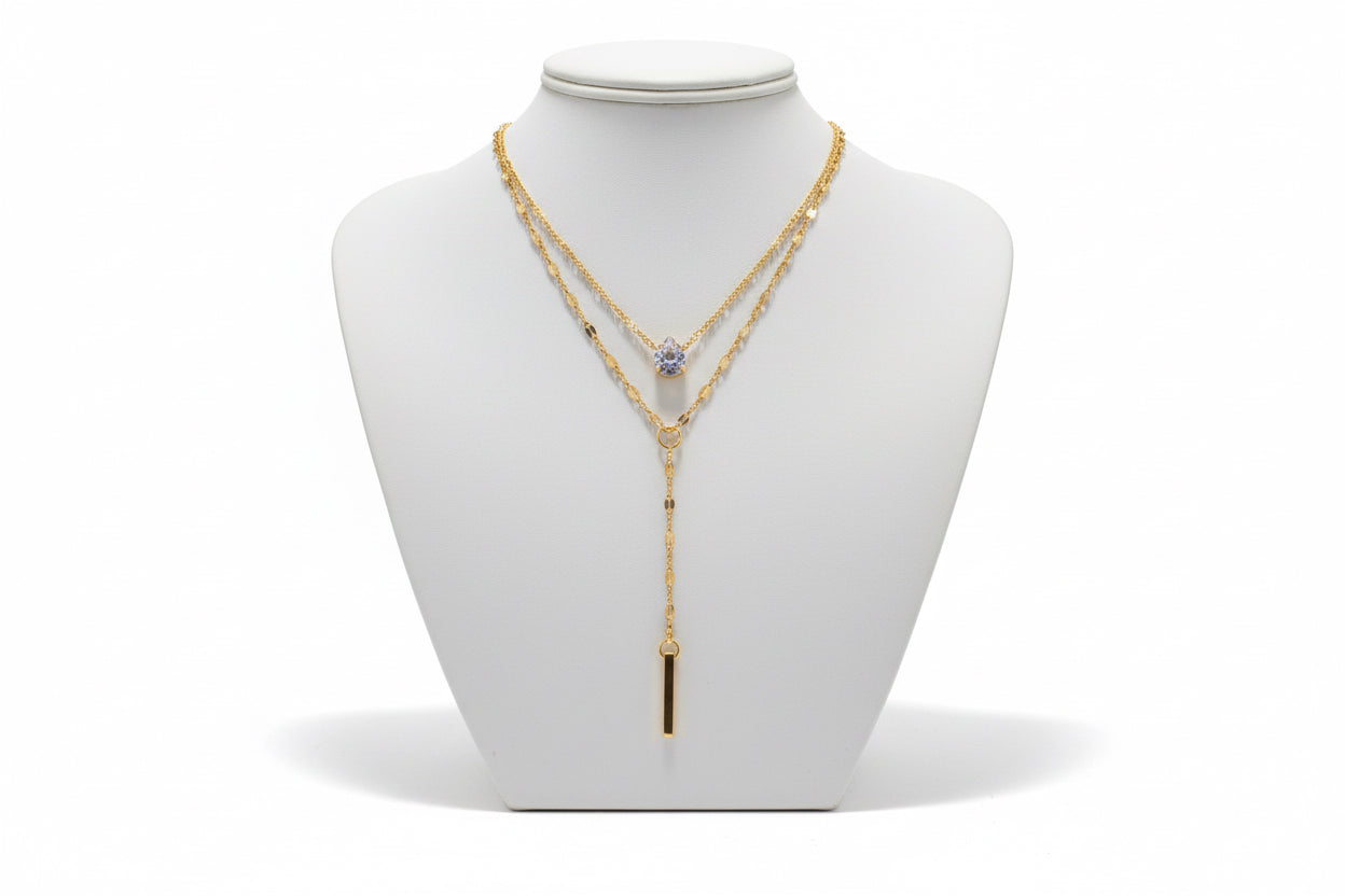Gold necklace with a pendant on a mannequin bust against a neutral background