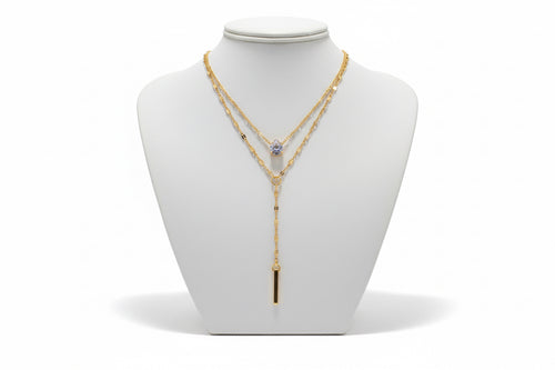 Gold necklace with a pendant on a mannequin bust against a neutral background