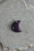 Crescent moon-shaped pendant on a light gray background
