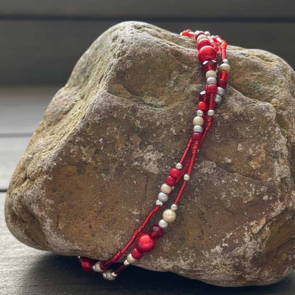 Red beaded triple bracelet set on a white mannequin arm