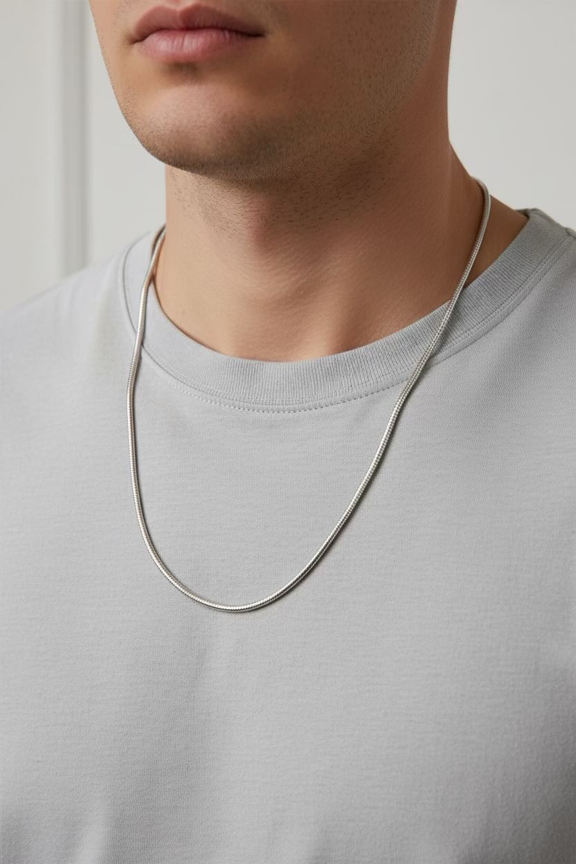 A delicate silver chain necklace on a model wearing a grey top and white background.