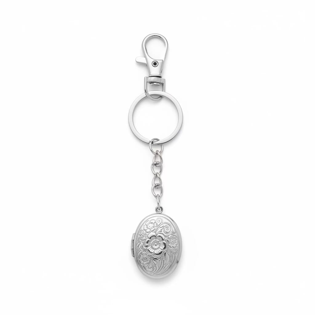 A polished silver metal keychain featuring a lobster clasp, a split key ring, a short chain, and a hanging oval flowered patterned locket pendant, shown on a plain white background.