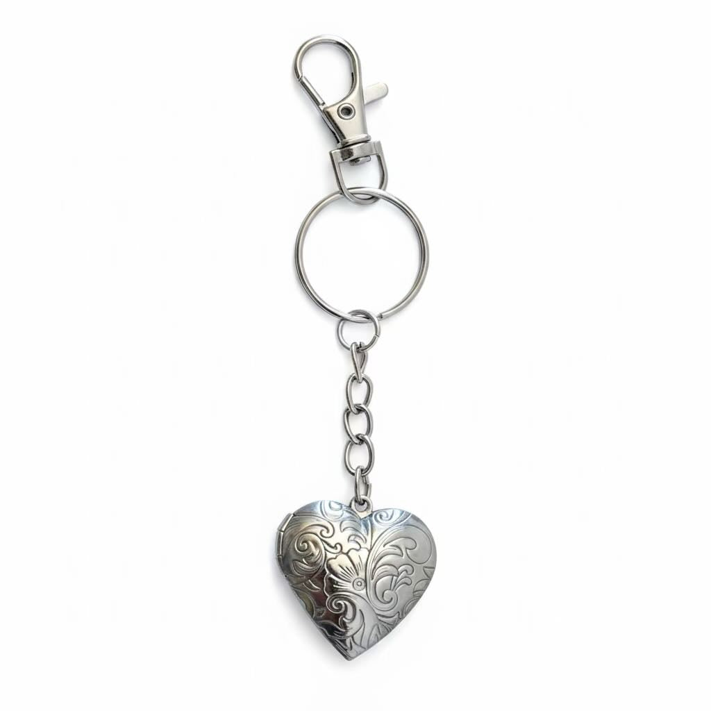 A silver-toned metal keychain featuring an engraved heart-shaped locket pendant, attached to a split key ring and lobster clasp, shown on a plain white background.