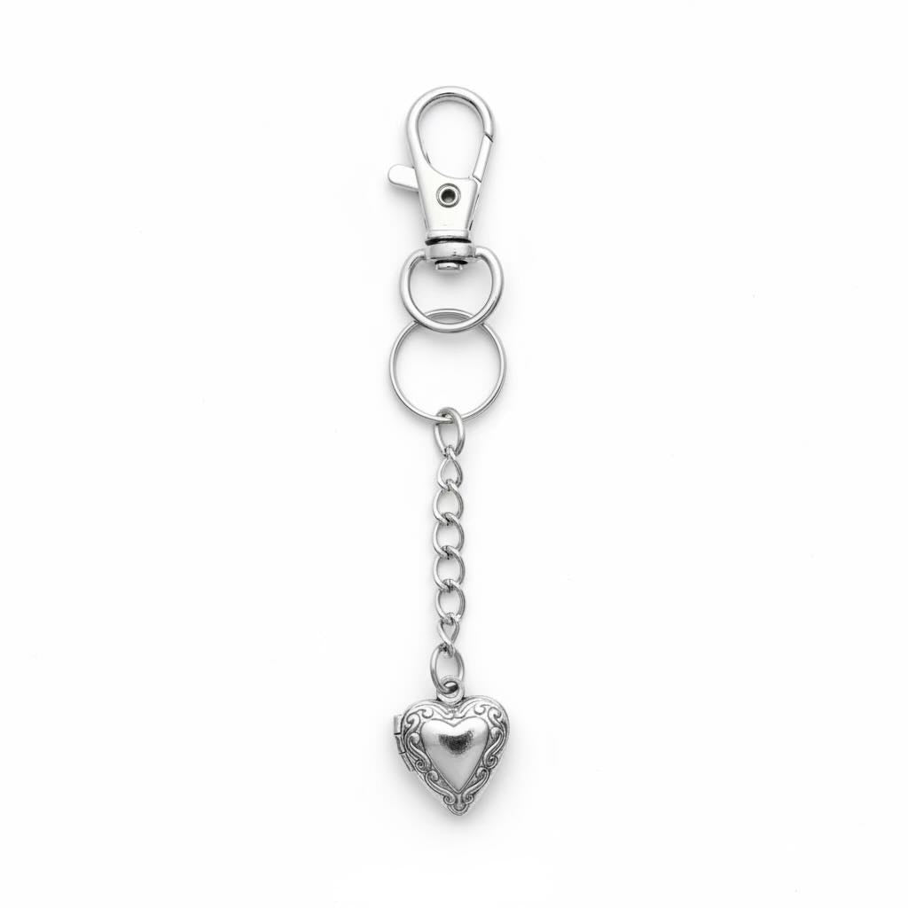 A silver-toned metal keychain featuring a lobster clasp, a split ring, a short chain, and an ornate heart-shaped locket pendant, shown on a plain white background.