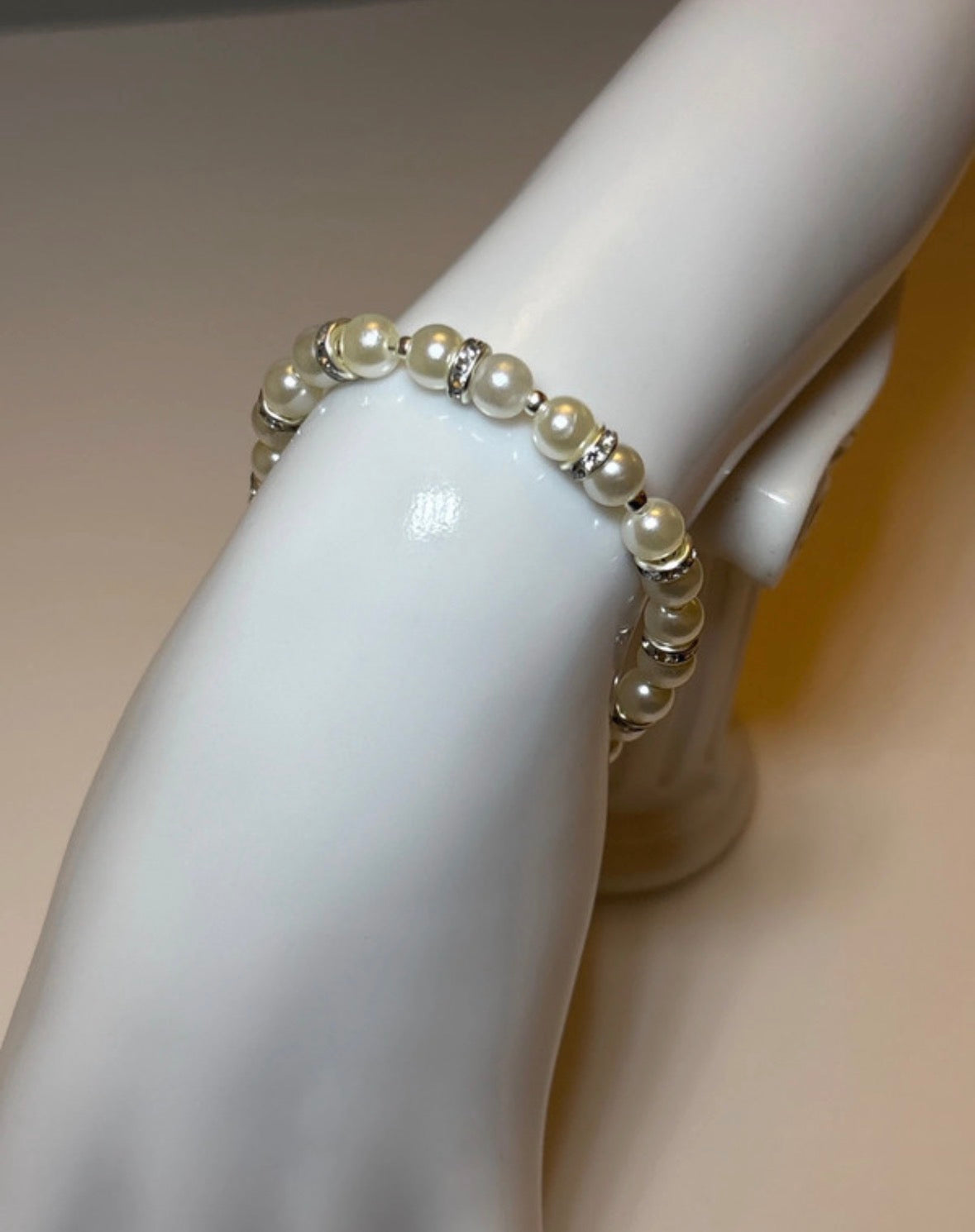 Pearl bracelet on a mannequin wrist with a plain background
