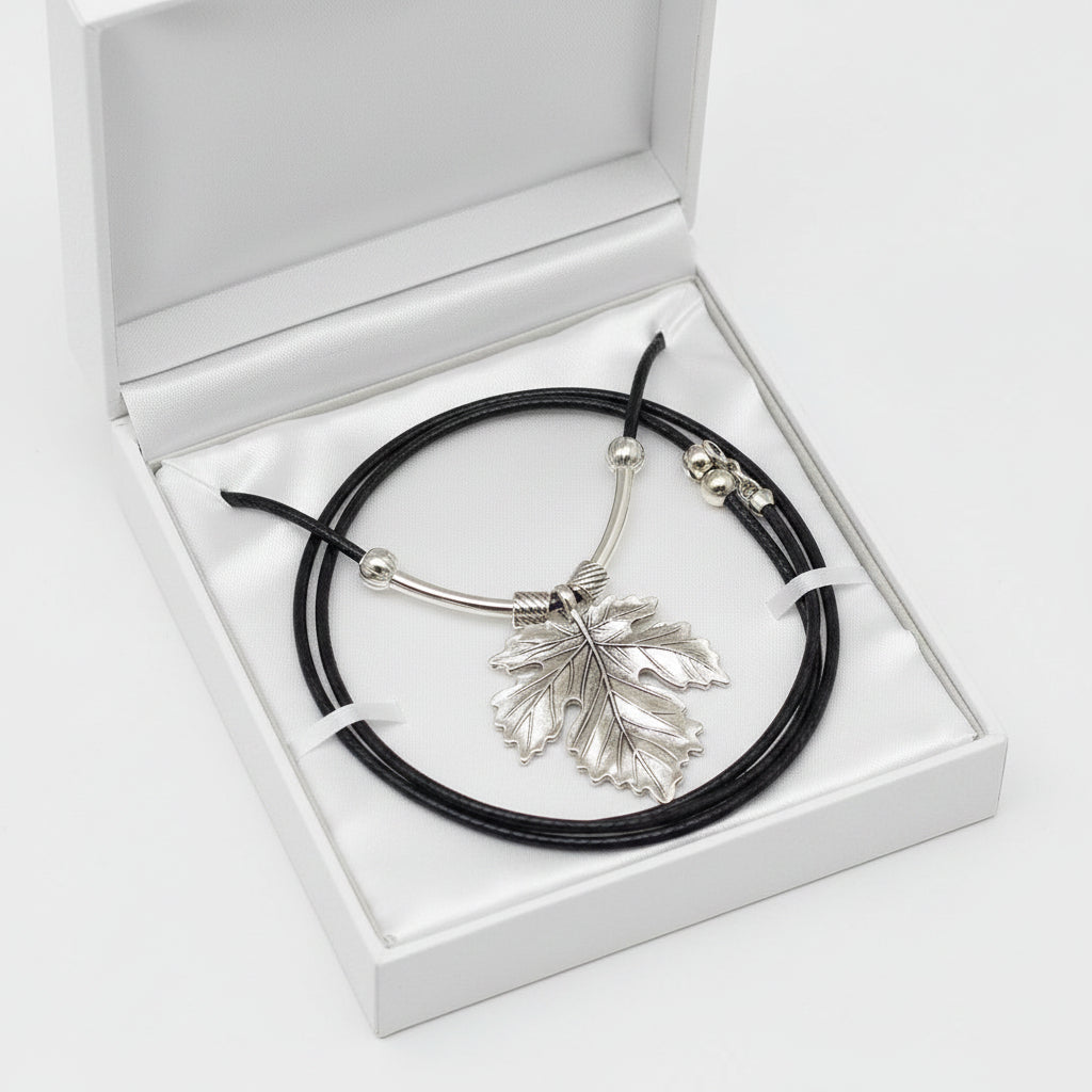 A silver leaf pendant necklace on a black cord, displayed in a white gift box.