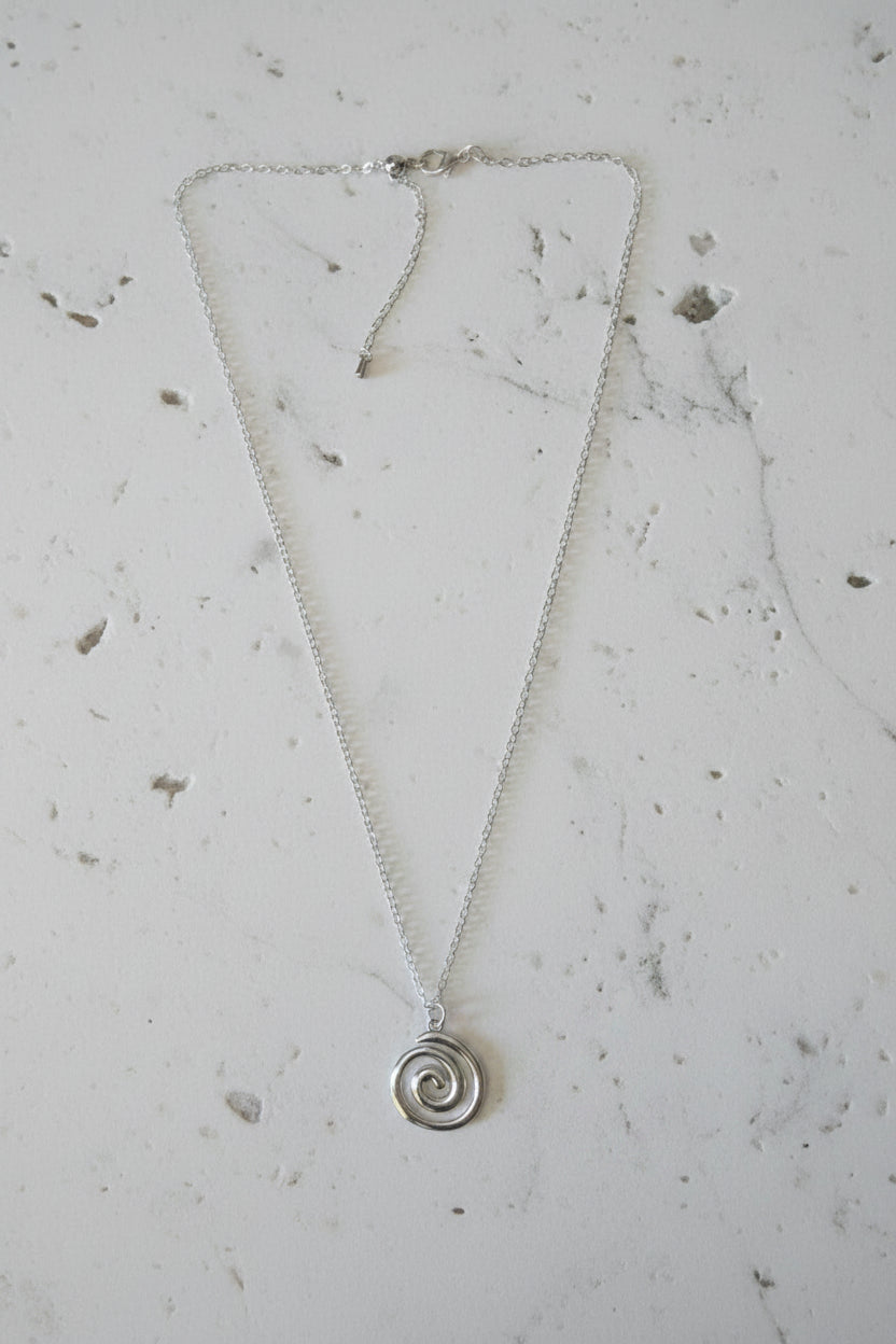 Silver necklace with a spiral pendant on a light gray background