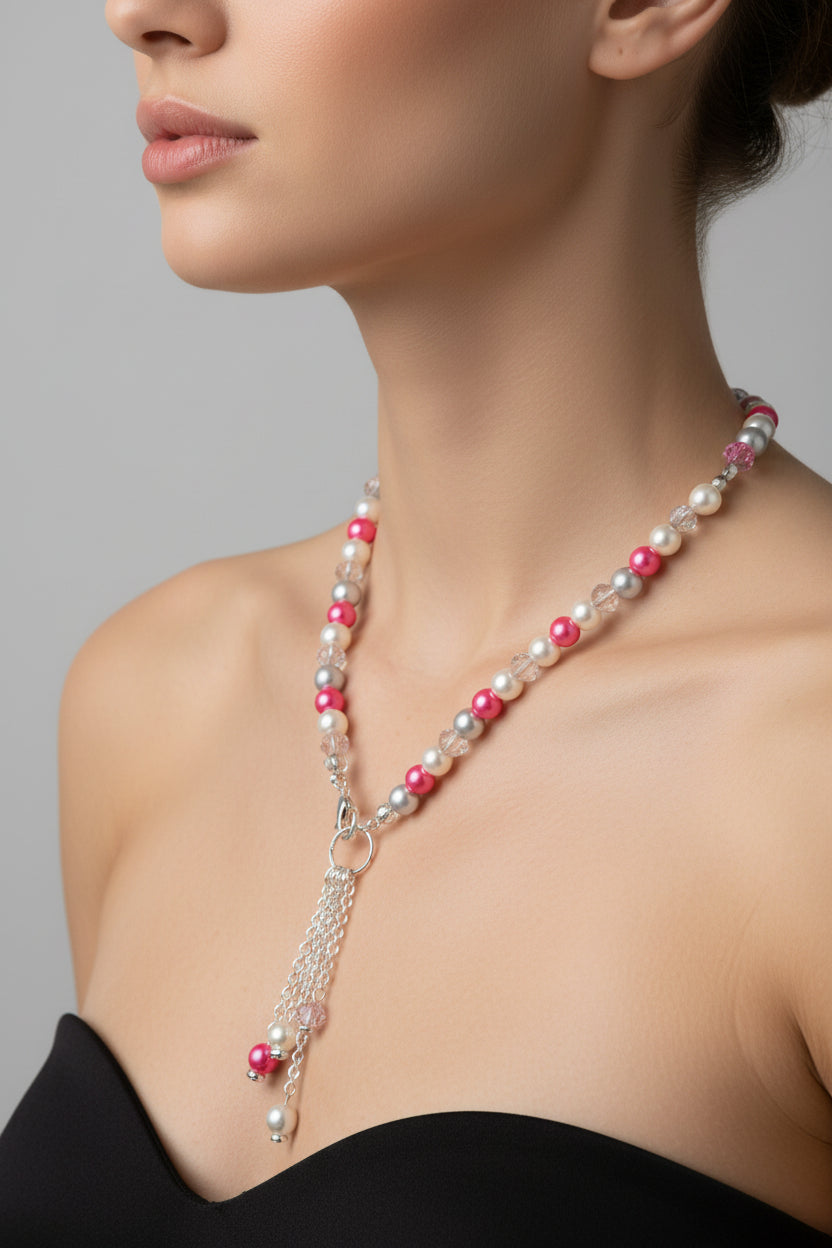 Pearl necklace with pink beads worn by a model on a gray background