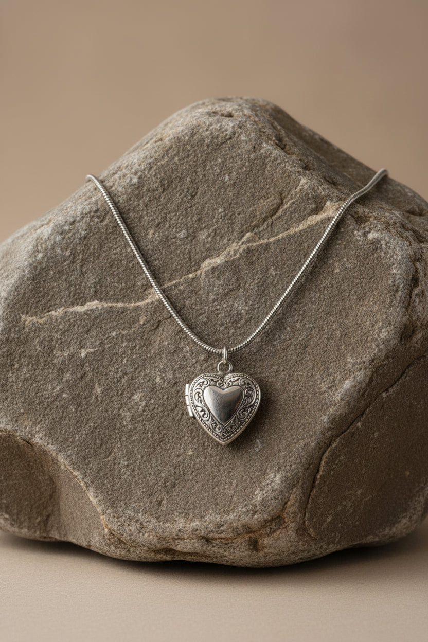 Silver heart-shaped pendant necklace on a large brown stone.