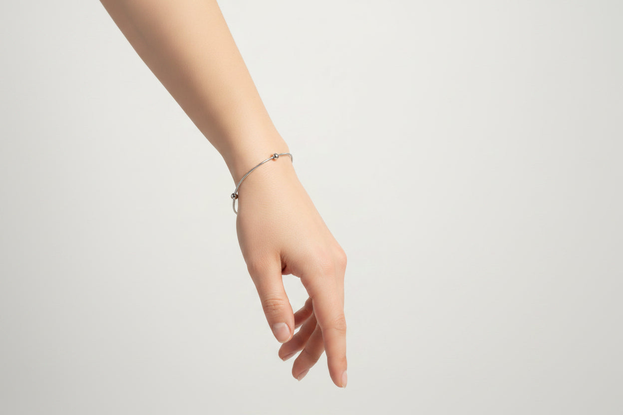 Hand wearing a bracelet on a light gray background