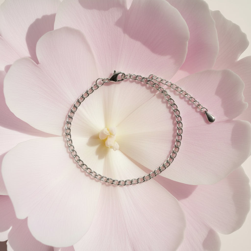 Silver chain bracelet on a large pale pink petal 
