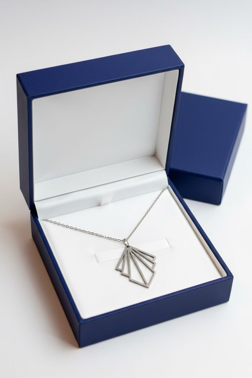 A silver art deco fan pendant necklace displayed inside an open navy blue jewelry box with a white insert, alongside a closed matching box on a light gray background.