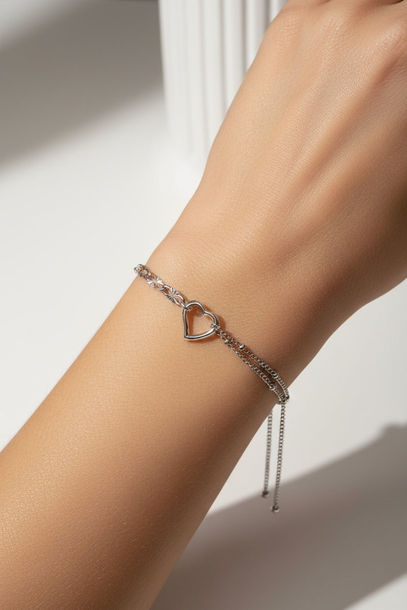 Silver double chain bracelet with a heart charm on a model's wrist