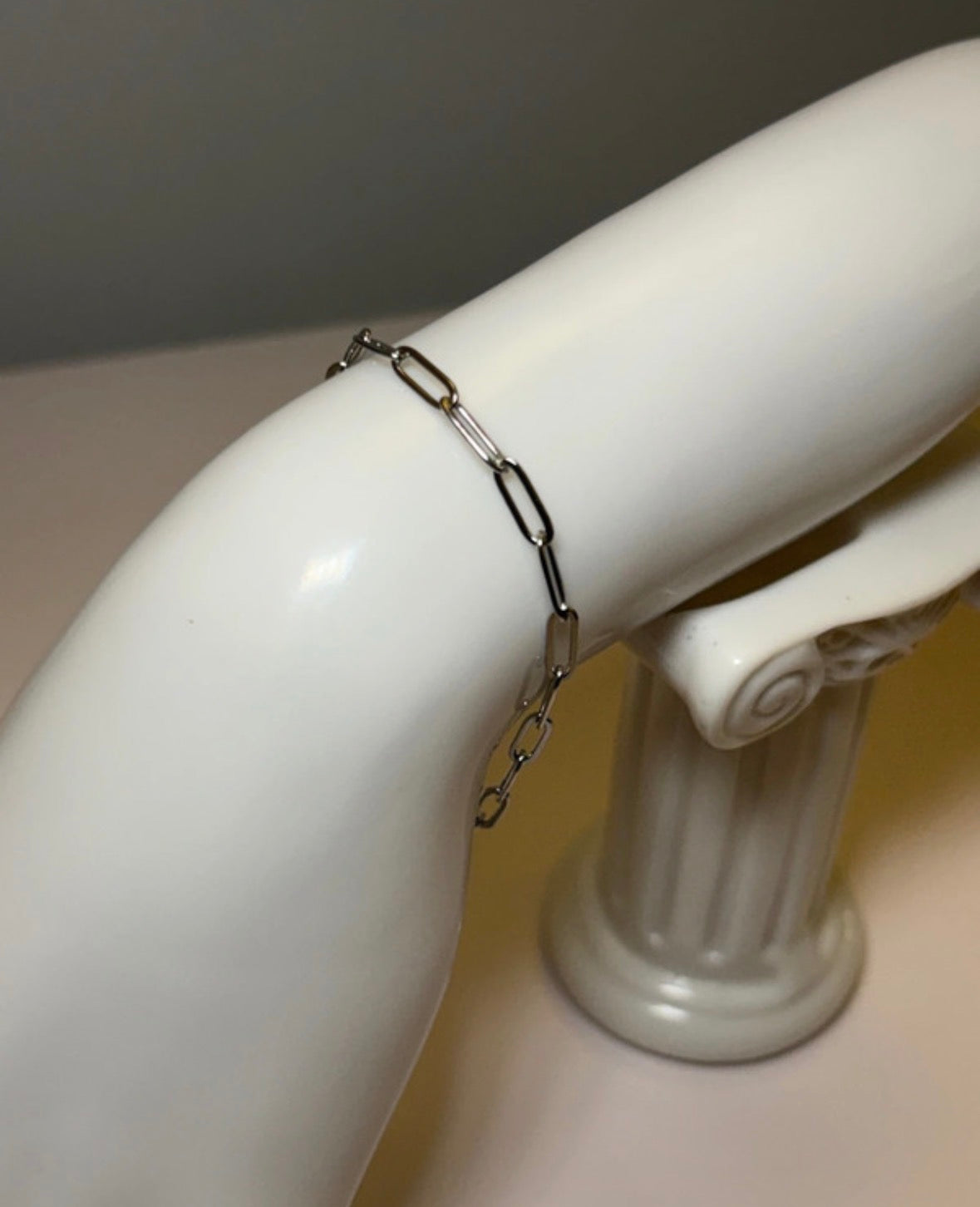 Silver chain bracelet on a white mannequin arm against a neutral background