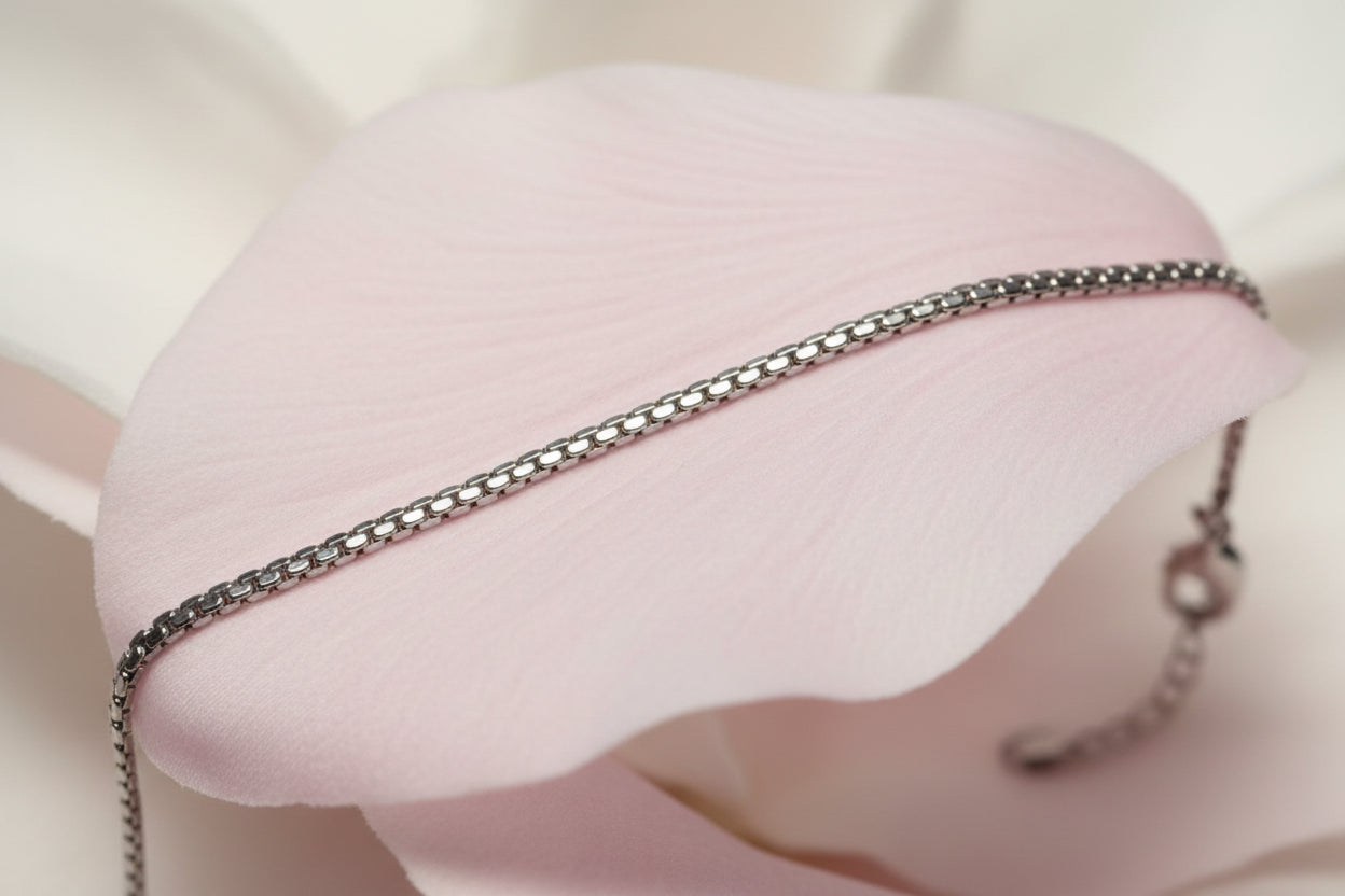 Silver chain bracelet on a pale pink petal 
