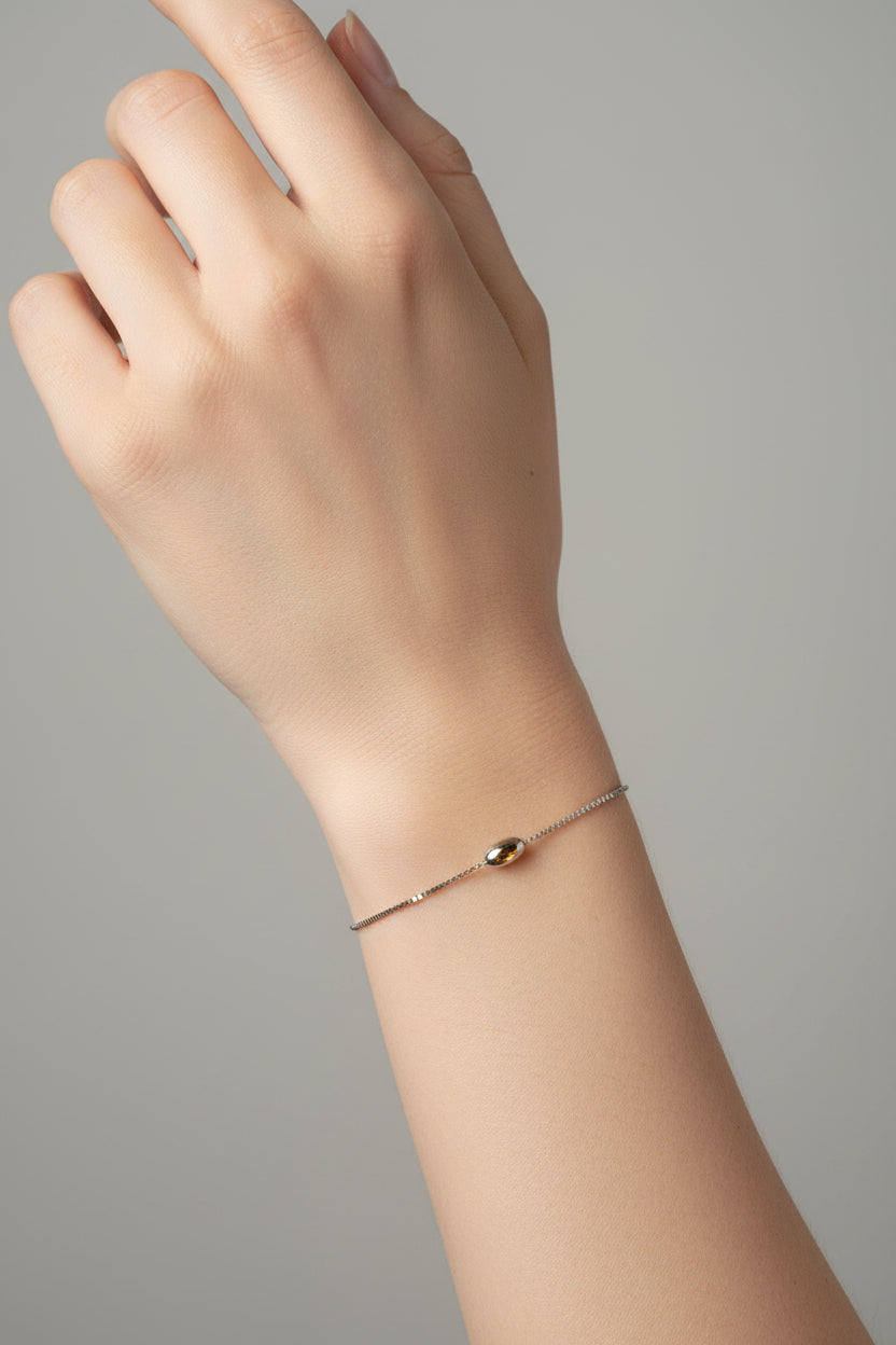 Hand wearing a delicate bracelet on a neutral background