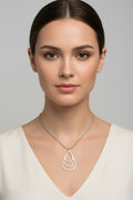A silver-toned teardrop pendant necklace with three nested curved rings, displayed on a model and grey background.