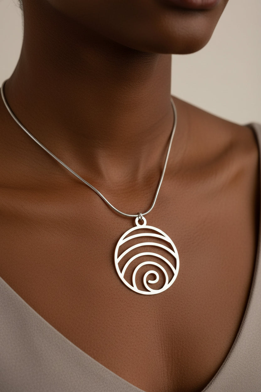A silver-tone spiral shell pendant necklace displayed on a model.