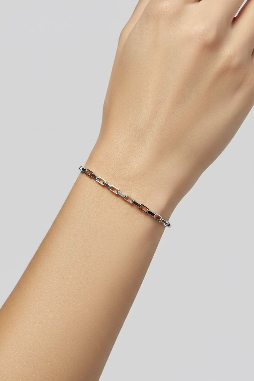 A delicate silver chain bracelet with alternating dark brown and clear rhinestone links, shown worn on a person's wrist against a light gray background.