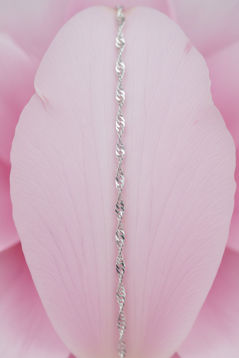 Silver chain bracelet on a large pale pink petal