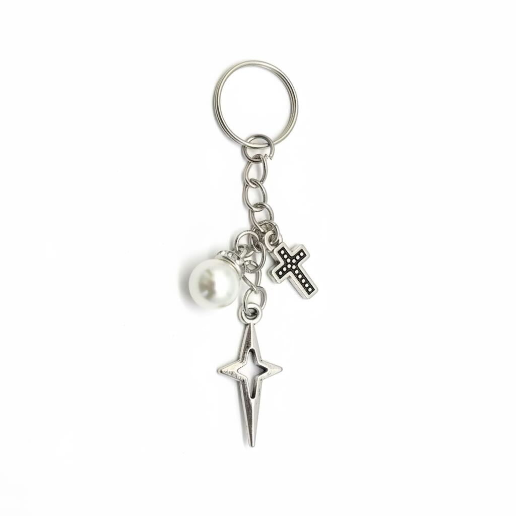 Silver-tone metal keyring/keyrings with a split ring, a dangling pearl bead, a small Bethlehem star charm, and a larger starburst charm on a white background.