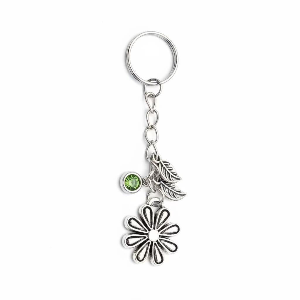 A silver-toned metal keyring/keyrings featuring a flower charm, a leaf charm, and a small round green gemstone, shown on a plain white background.