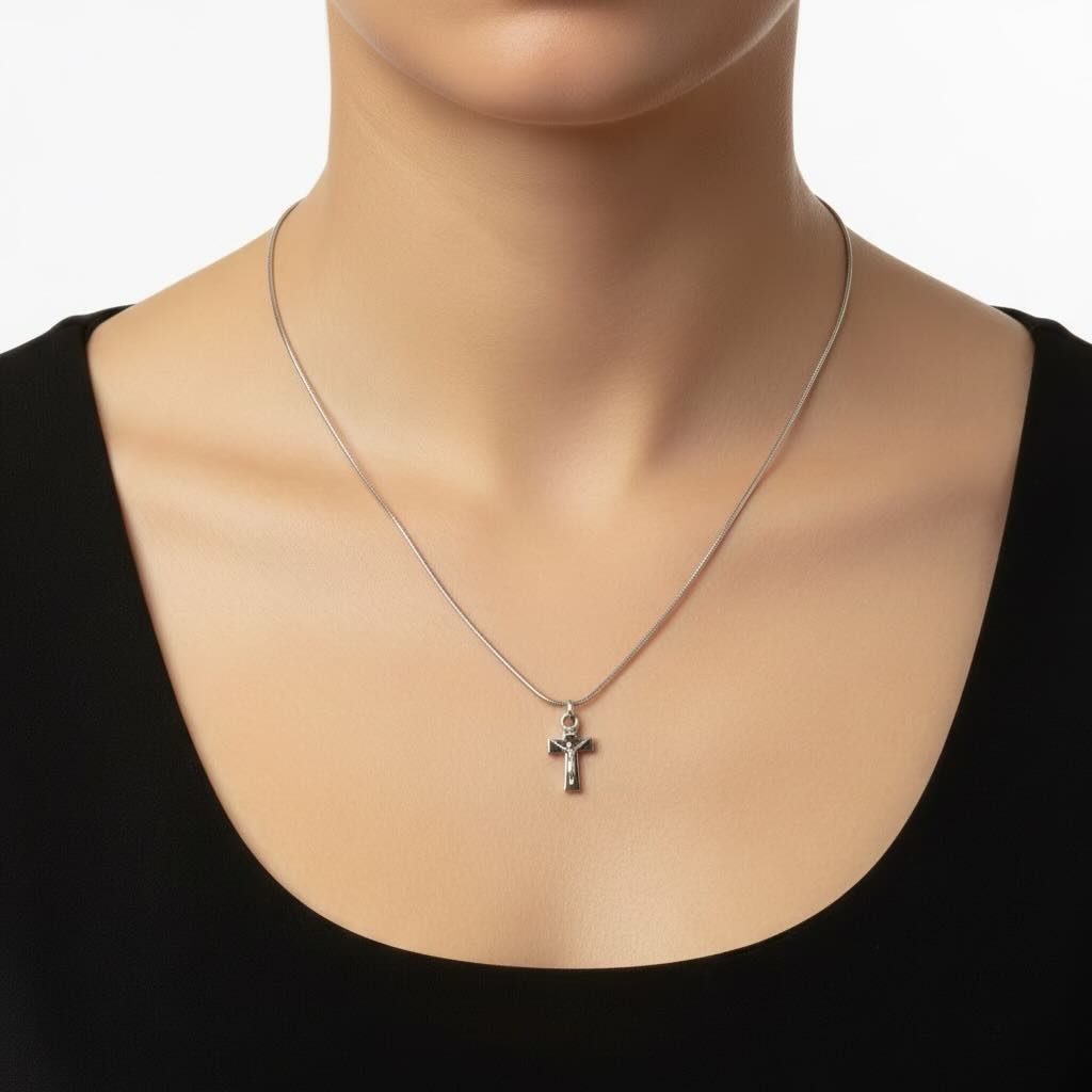 Silver necklace with a cross pendant worn by a person in a black top