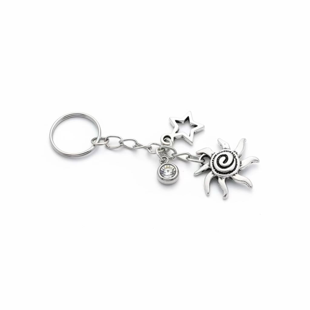 A silver-toned metal keyring/keyrings featuring a circular key ring, a short chain, aa small round charm, a swirling starburst charm, and a sunburst charm, shown on a plain white background.
