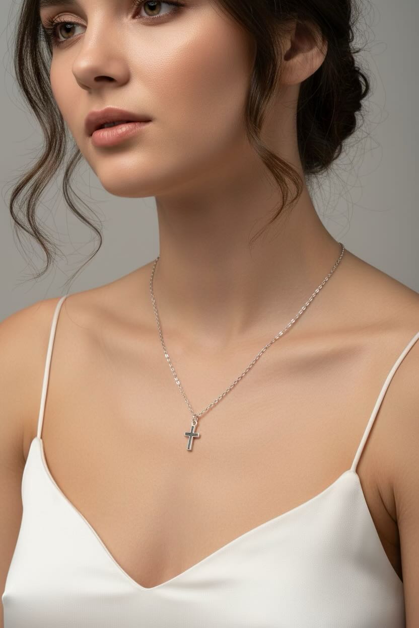 Woman wearing a silver necklace with a cross pendant on a neutral background