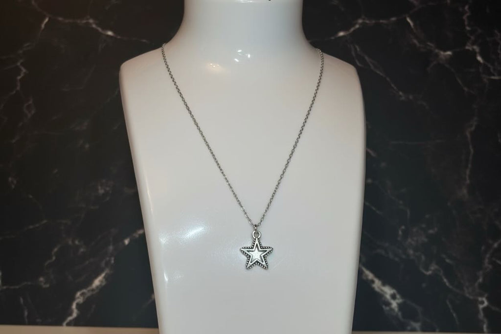 A silver star pendant necklace displayed on a white mannequin bust against a dark marble-patterned background.