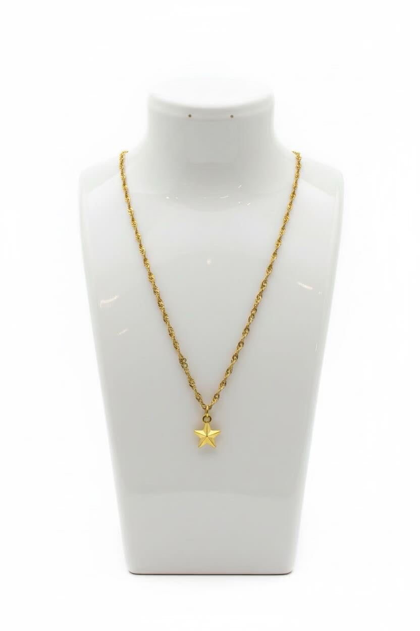 A gold chain necklace with a small star-shaped pendant, displayed on a white jewelry bust against a white background.
