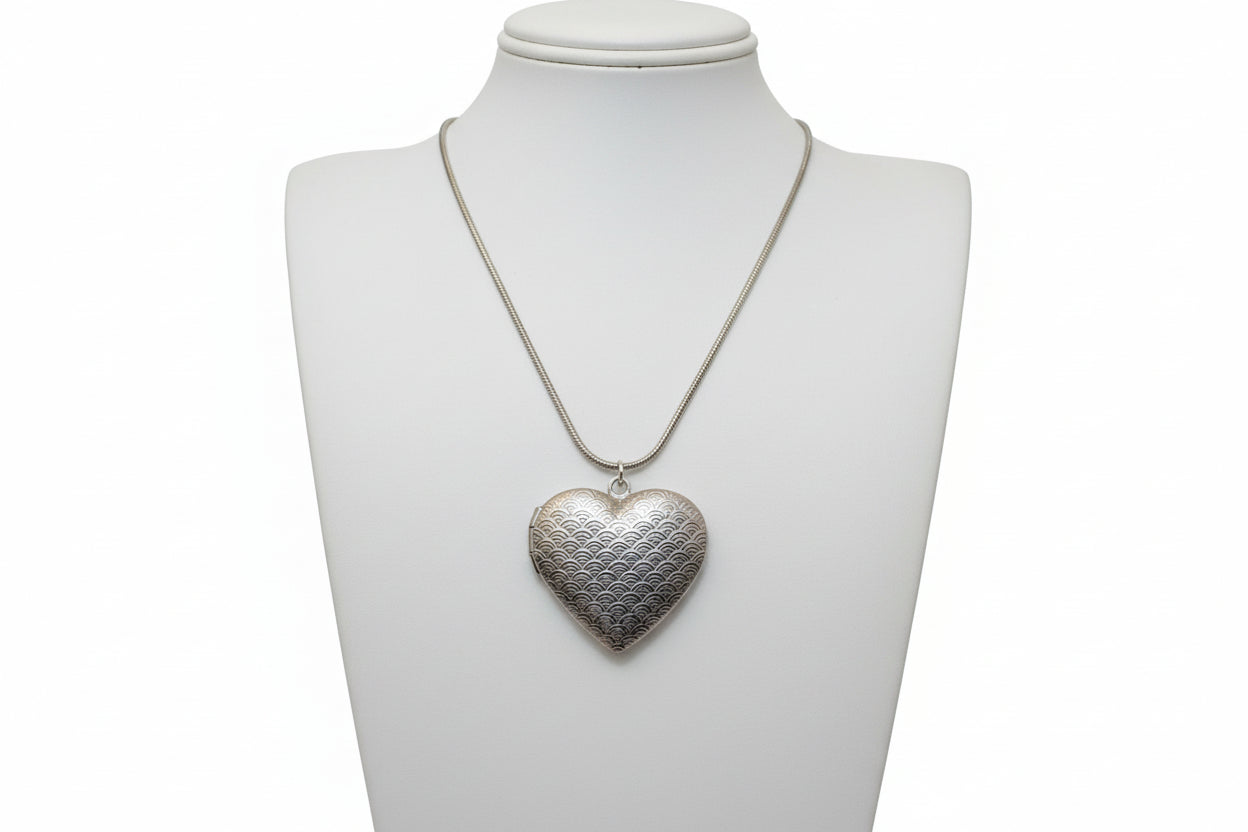 Silver heart-shaped pendant on a chain against a white background