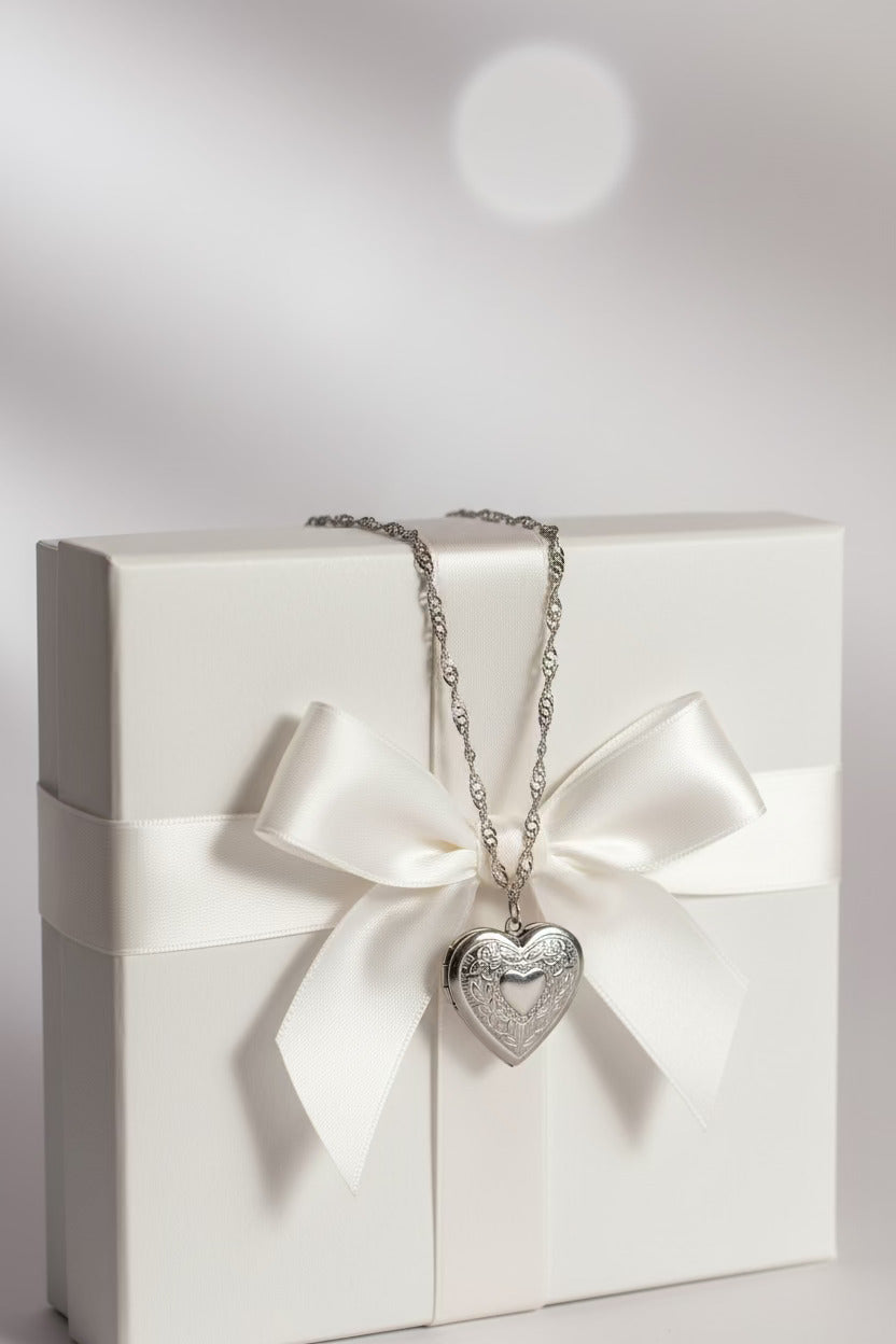 Silver heart-shaped locket on water wave necklace on a white gift box with a bow