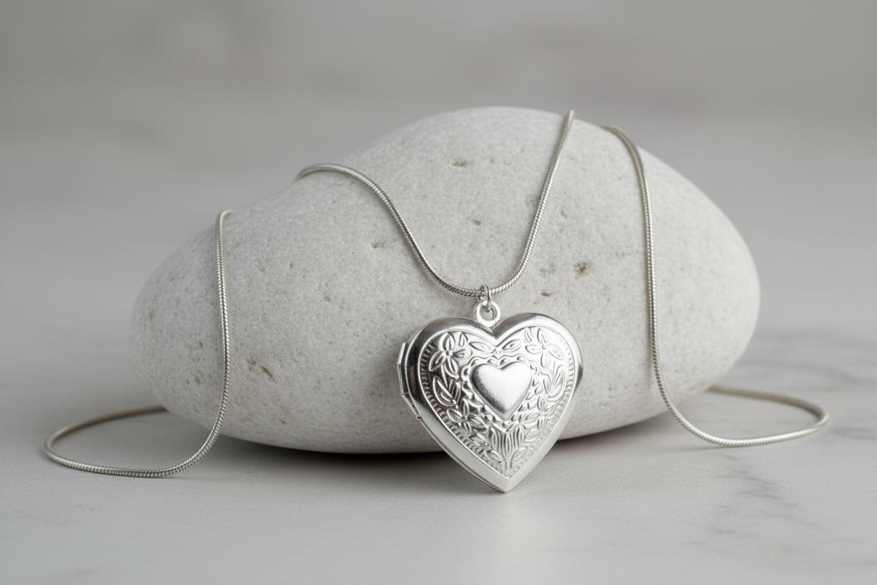 Silver stainless steel heart-shaped locket necklace on a stone