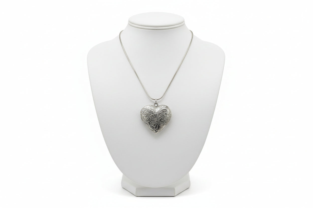 Silver heart-shaped locket on snake chain necklace on a mannequin neck