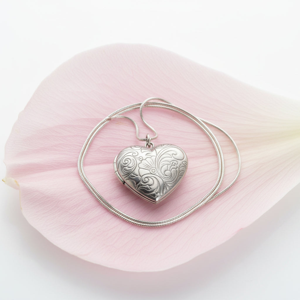 Silver heart-shaped locket snake chain necklace on a large petal
