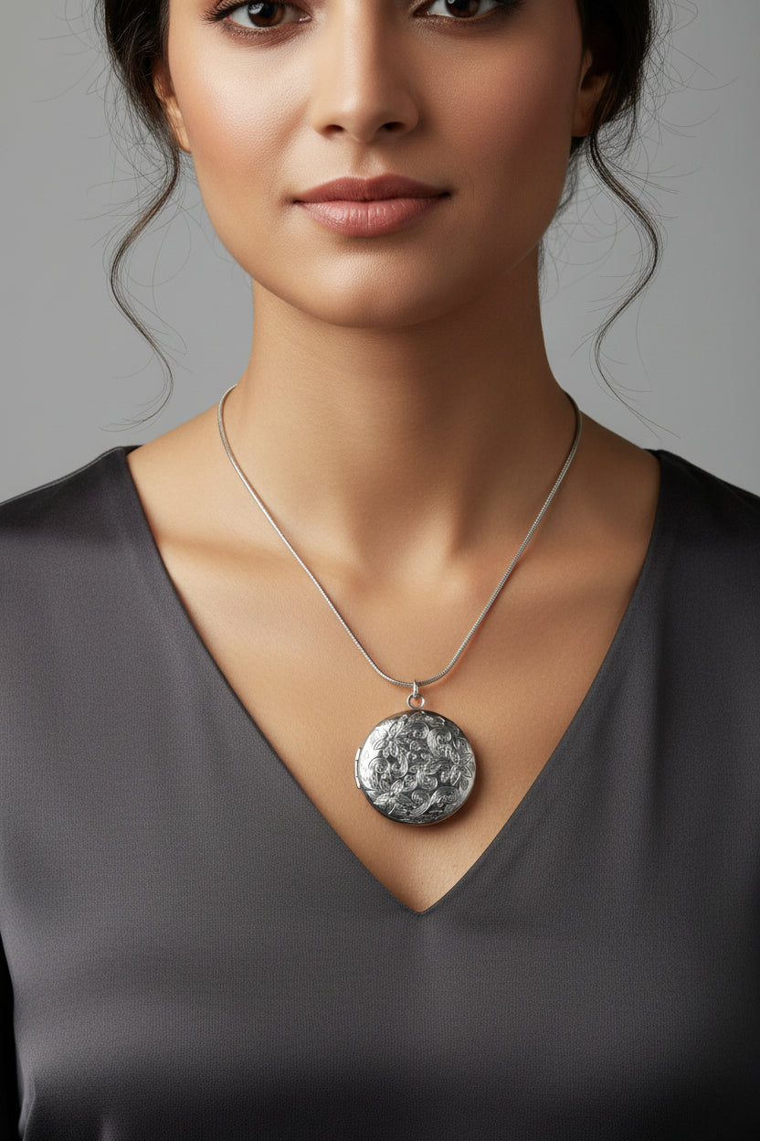Silver necklace with a round patterned locket, intricately designed on a model